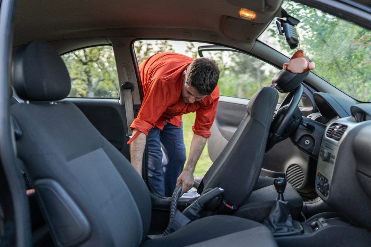 man vacuuming out european car